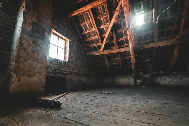 Leerer Dachboden eines Altbaus mit Holzbalken und Licht durch ein Dachfenster